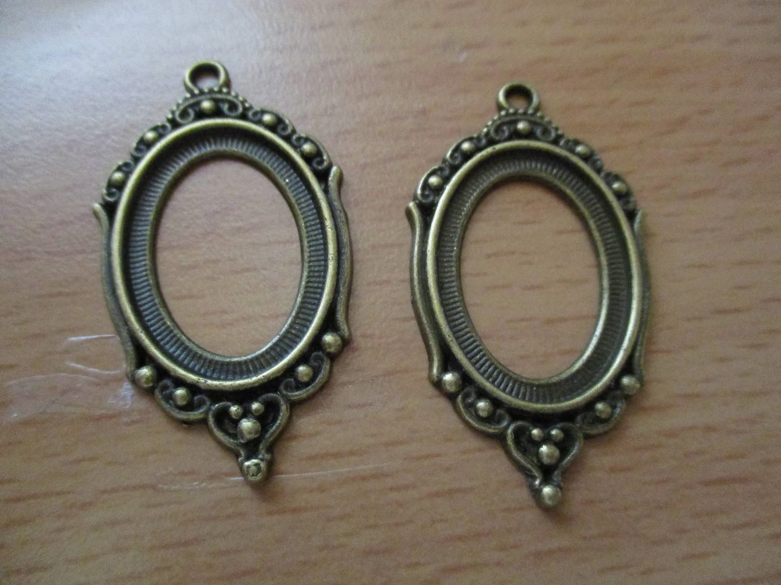 Ovális díszes medálalap, antik bronz színű, 42x23 mm, 25x18 mm-es lencséhez